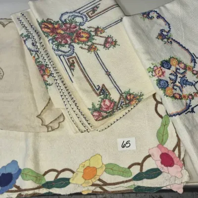Sale Photo Thumbnail #98: Collection of vintage hand-embroidered and cross-stitched table linens, including tablecloths and runners with colorful floral motifs.