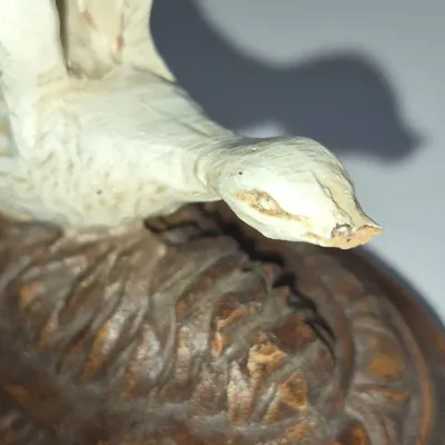 Sale Photo Thumbnail #258: Hand-carved wooden bird figurine, featuring a painted white body mounted on a textured, dark-stained base.