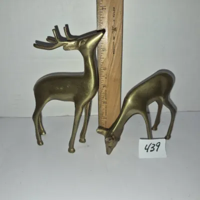 Sale Photo Thumbnail #763: Pair of mid-century solid brass deer figurines, including a standing buck and a grazing doe, measuring around 6 inches tall.