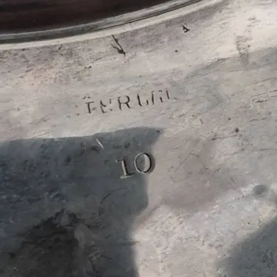 Sale Photo Thumbnail #906: Extreme close-up of a maker's mark and the number 10 stamped into a metallic surface.