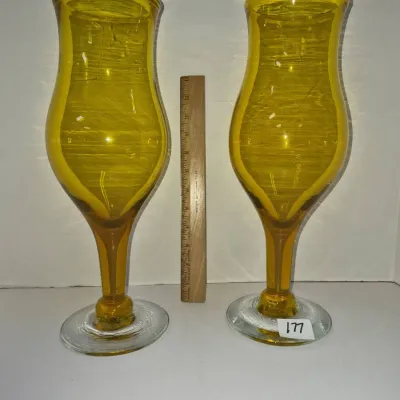 Sale Photo Thumbnail #305: Pair of vintage hand-blown amber glass hurricane-style floor or oversized vases featuring clear glass bases, measuring approximately 12 inches tall.
