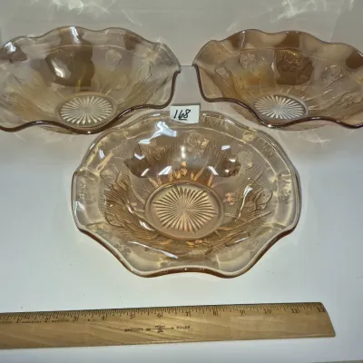 Sale Photo Thumbnail #289: Set of three vintage marigold carnival glass bowls with ruffled edges and floral relief patterns.