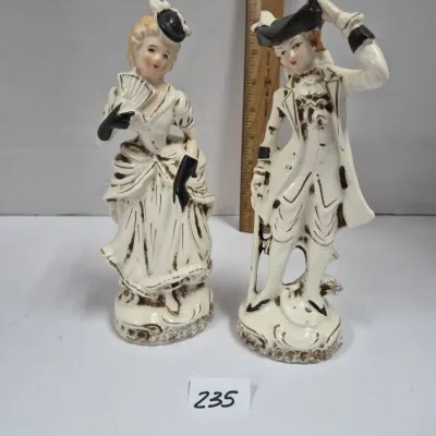 Sale Photo Thumbnail #402: Pair of vintage porcelain colonial-style figurines featuring a man and woman in period attire with black and gold accents.