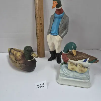 Sale Photo Thumbnail #451: Set of three ceramic duck figurines, including an anthropomorphic dressed mallard, a duck with ducklings, and a small duck box, shown with a ruler for scale.