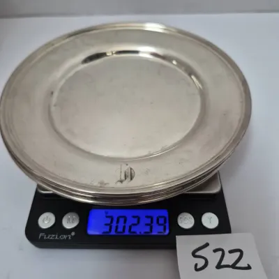 Sale Photo Thumbnail #901: Monogrammed sterling silver plate resting on a digital scale displaying a weight of 302.39 grams.