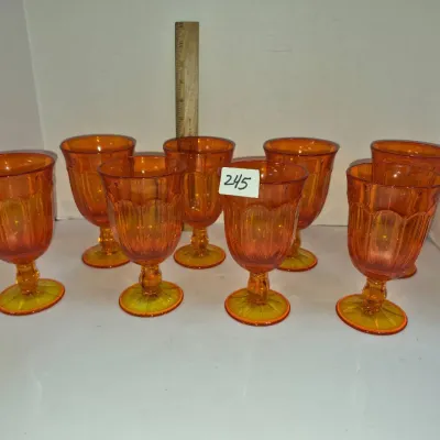 Sale Photo Thumbnail #420: Set of eight vintage amberina glass stemmed goblets featuring a paneled design and a gradient orange-to-yellow color.