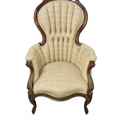 Sale Photo Thumbnail #109: Victorian-style high-back armchair featuring carved wood trim with floral cresting and tufted cream damask upholstery.