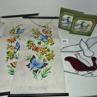 Sale Photo Thumbnail #829: Collection of vintage home decor including a pair of butterfly-printed hanging wall scrolls, two duck-themed framed prints, and a stained glass bird and sleigh set.