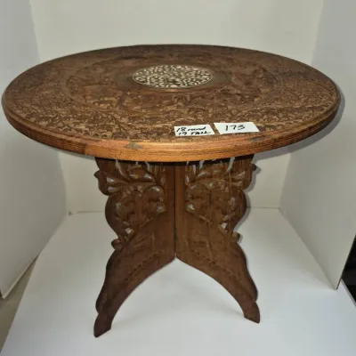 Sale Photo Thumbnail #298: Hand-carved Anglo-Indian wooden side table featuring floral inlay on top and a collapsible fretwork base, measuring 18 inches round by 19 inches tall.