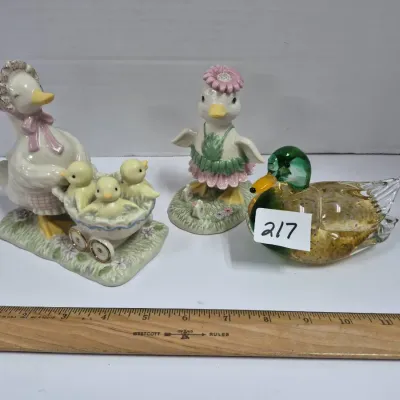 Sale Photo Thumbnail #371: Collection of duck-themed decorative figurines, including two painted porcelain mother and duckling pieces alongside a Murano-style art glass mallard duck paperweight.
