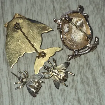 Sale Photo Thumbnail #869: Collection of four vintage gold-tone costume jewelry brooches, featuring animal and insect designs including an owl, a fish marked 'Spain', and two small bee pins.