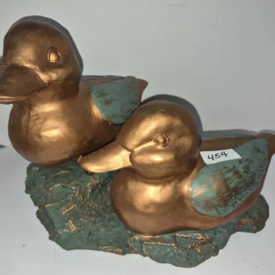 Sale Photo Thumbnail #786: Pair of duck figurines finished in bronze paint with green patina accents, set on a textured green base.