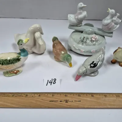 Sale Photo Thumbnail #252: Collection of seven vintage porcelain and ceramic duck figurines, including a duck seesaw music box base.