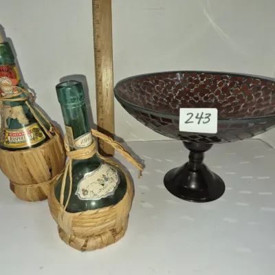 Sale Photo Thumbnail #418: Pair of vintage Chianti wine bottles wrapped in woven raffia, displayed alongside a dark red mosaic pedestal bowl.