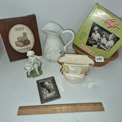 Sale Photo Thumbnail #830: Assortment of vintage decorative items including a framed cross-stitch sign, porcelain pitchers, a gentleman figurine, a small religious picture, and a Loop Craft weaving loom in its original box.