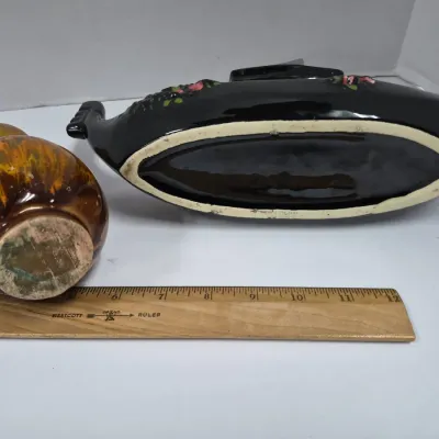 Sale Photo Thumbnail #405: Underside of a vintage drip-glazed ceramic vase and a black ceramic gondola-style planter, shown next to a wooden ruler for scale.