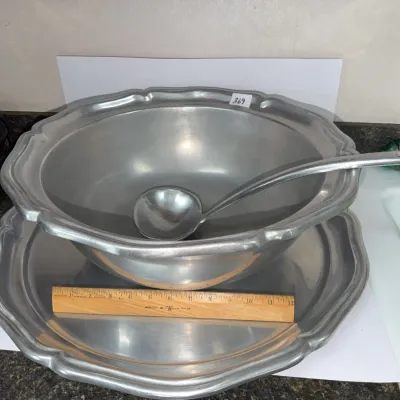 Sale Photo Thumbnail #639: Large pewter punch bowl set including a matching underplate and soup ladle with scalloped rim detailing.