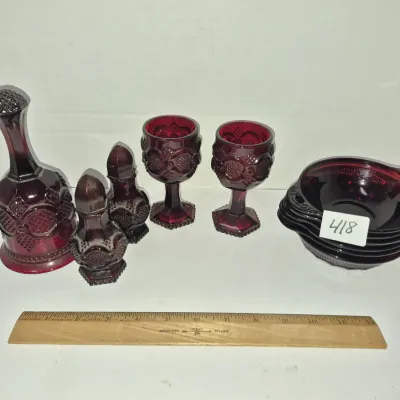 Sale Photo Thumbnail #733: Collection of vintage ruby red pressed glass tableware, including a dinner bell, salt and pepper shakers, stemware goblets, and a stack of small nappy bowls.