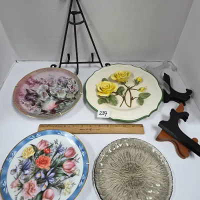 Sale Photo Thumbnail #409: Collection of decorative plates and display stands, featuring three floral porcelain plates and a textured clear glass plate.