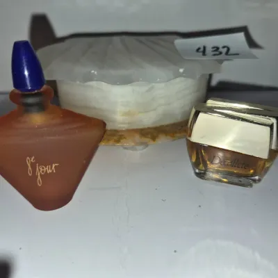 Sale Photo Thumbnail #750: Collection of vintage miniature perfume bottles, including a frosted brown 8e Jour bottle and a small Décolleté flacon, alongside a shell-shaped alabaster trinket box.