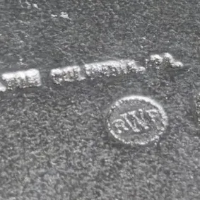 Sale Photo Thumbnail #640: Close-up detail of a Wilton Armetale maker's mark stamped into a pewter-like metal piece.