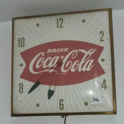 Sale Photo Thumbnail #541: Vintage mid-century square Coca-Cola advertising electric wall clock featuring a red fishtail logo and starburst graphic dial in a gold-tone metal frame.