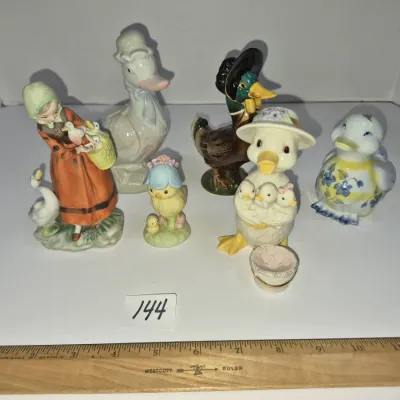 Sale Photo Thumbnail #244: Collection of seven vintage ceramic figurines, including ducks, chicks, and a goose girl, shown with a wooden Westcott ruler for scale.