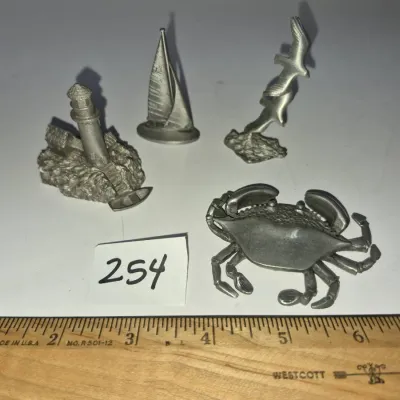 Sale Photo Thumbnail #433: Set of four nautical-themed pewter miniature figurines including a crab, lighthouse, sailboat, and seagull.