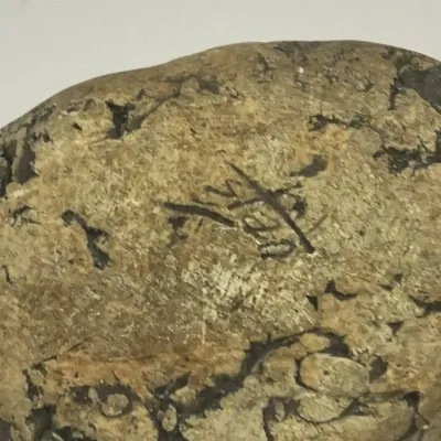 Sale Photo Thumbnail #327: Close-up view of the artist's signature incised into the bottom of an aged ceramic or stone piece.