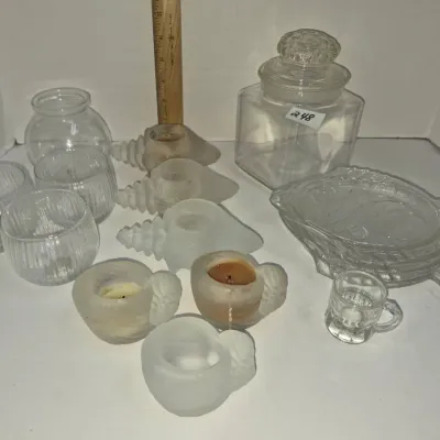 Sale Photo Thumbnail #423: Assortment of clear and frosted glass items including a large apothecary jar, seashell-shaped candle holders, ribbed votives, and a fish-shaped serving dish.