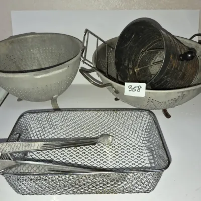Sale Photo Thumbnail #621: Collection of vintage metal kitchenware including aluminum strainers, a flour sifter, serving tongs, and a wire mesh basket.