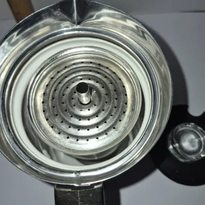 Sale Photo Thumbnail #739: Interior overhead view of a vintage stainless steel stovetop coffee percolator showing the basket spreader plate and stem.