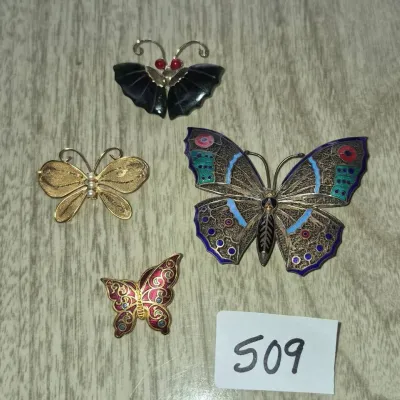 Sale Photo Thumbnail #877: Collection of four vintage butterfly brooches featuring filigree, enamel, and carved stone detailing.