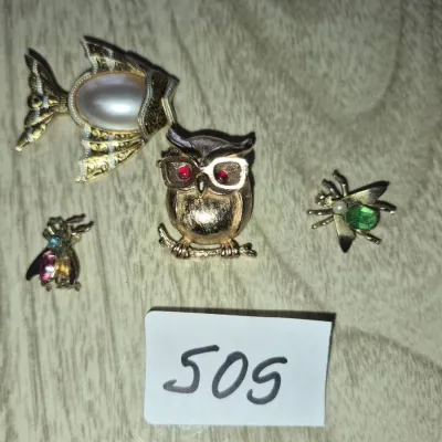 Sale Photo Thumbnail #868: Collection of four vintage gold-tone animal-themed brooches, including a fish with faux-pearl body, an owl with rhinestone eyes, and two insect pins with colorful cabochons.