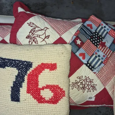 Sale Photo Thumbnail #67: Collection of Americana and Bicentennial-themed textiles, featuring a cross-stitched '76 pillow, patriotic quilted fabric, and red and white embroidered pillow shams.