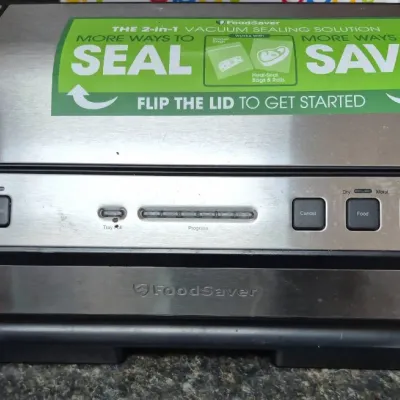 Sale Photo Thumbnail #675: FoodSaver 2-in-1 vacuum sealing machine featuring a stainless steel finish and handheld sealer attachment.