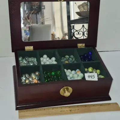 Sale Photo Thumbnail #771: Dark wood display case with a mirror-lined lid containing various colorful glass marbles sorted into green felt-lined compartments.