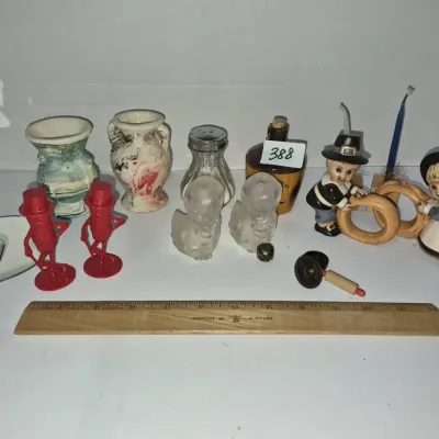 Sale Photo Thumbnail #680: Collection of vintage knick-knacks and figurines including red Mr. Peanut plastic figures, small ceramic vases, Thanksgiving-themed napkin rings, and glass items.