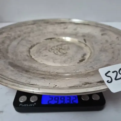 Sale Photo Thumbnail #914: Vintage tarnished silver-tone round platter, featuring an engraved center design and displayed on a Fuzion digital scale showing a weight of 299.32 grams.