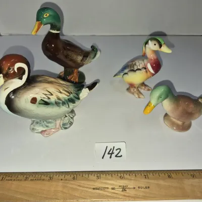 Sale Photo Thumbnail #240: Collection of four vintage painted ceramic duck figurines, including mallard and wood duck designs, shown next to a ruler for scale.
