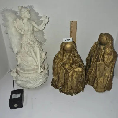 Sale Photo Thumbnail #760: White angel figurine with feather wings alongside a pair of gold-toned fabric-draped statues.