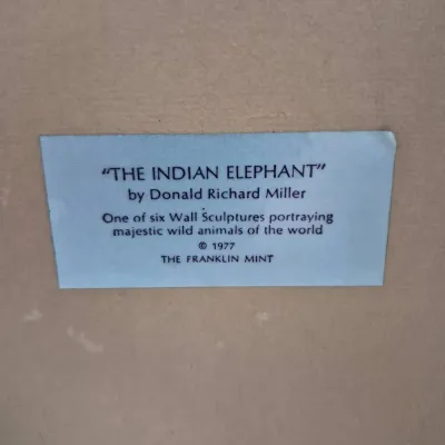 Sale Photo Thumbnail #589: Descriptive label for 'The Indian Elephant' wall sculpture by Donald Richard Miller for The Franklin Mint, copyright 1977.
