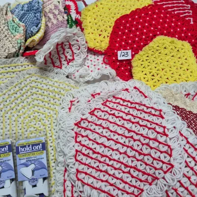 Sale Photo Thumbnail #202: Collection of handmade vintage crochet potholders, doilies, and dishcloths in vibrant colors alongside two packages of Hold On comforter clips.