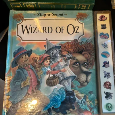 Play-a-Sound Wizard of Oz interactive storybook, factory sealed in original shrink wrap, positioned in front of green leather-bound Oz...