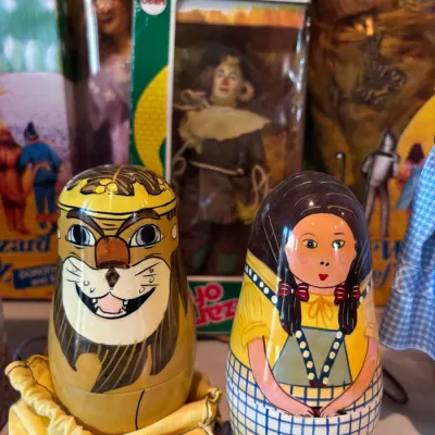 Hand-painted Wizard of Oz wooden nesting dolls, featuring the Cowardly Lion and Dorothy, displayed in front of vintage boxed Mego Wizard...