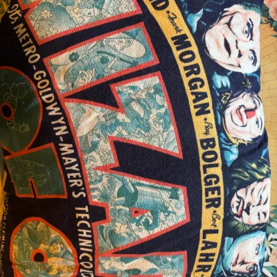 Sale Photo Thumbnail #133: Vintage-style 'The Wizard of Oz' printed throw pillow featuring classic movie poster graphics and cast illustrations.