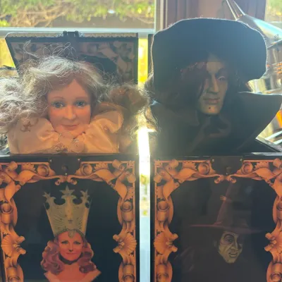 Pair of vintage Wizard of Oz musical jack-in-the-box collectibles, featuring Glinda the Good Witch and the Wicked Witch of the West.