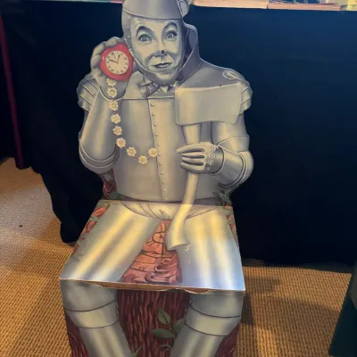 Vintage Wizard of Oz Tin Man folding cardboard chair featuring printed graphics of the character holding an axe and a heart pocket watch.