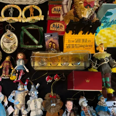 Collection of Wizard of Oz collectibles including hanging Christmas ornaments, figurines, a framed quote display, and packaged novelty...