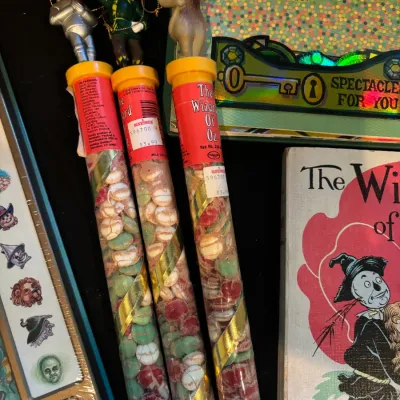 Sale Photo Thumbnail #103: Set of vintage Wizard of Oz candy containers topped with character toppers alongside a Wizard of Oz book and collectibles.